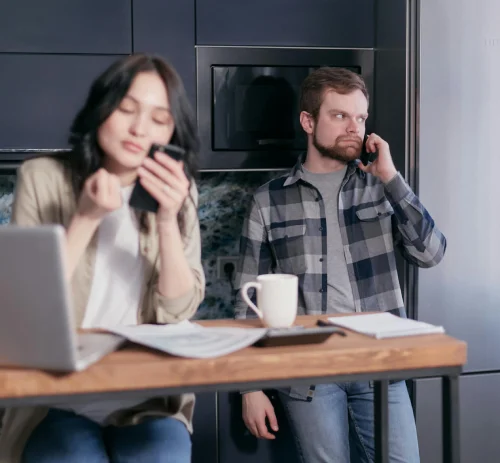 a man talking on his cellphone and a woman looking at her laptop